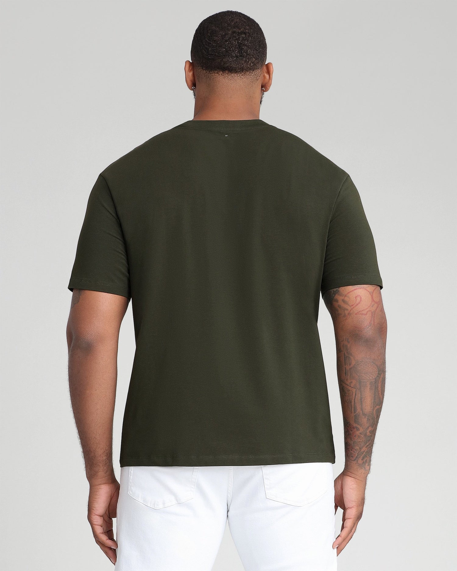 Man wearing olive green crew neck t-shirt with short sleeves, shown from back view.