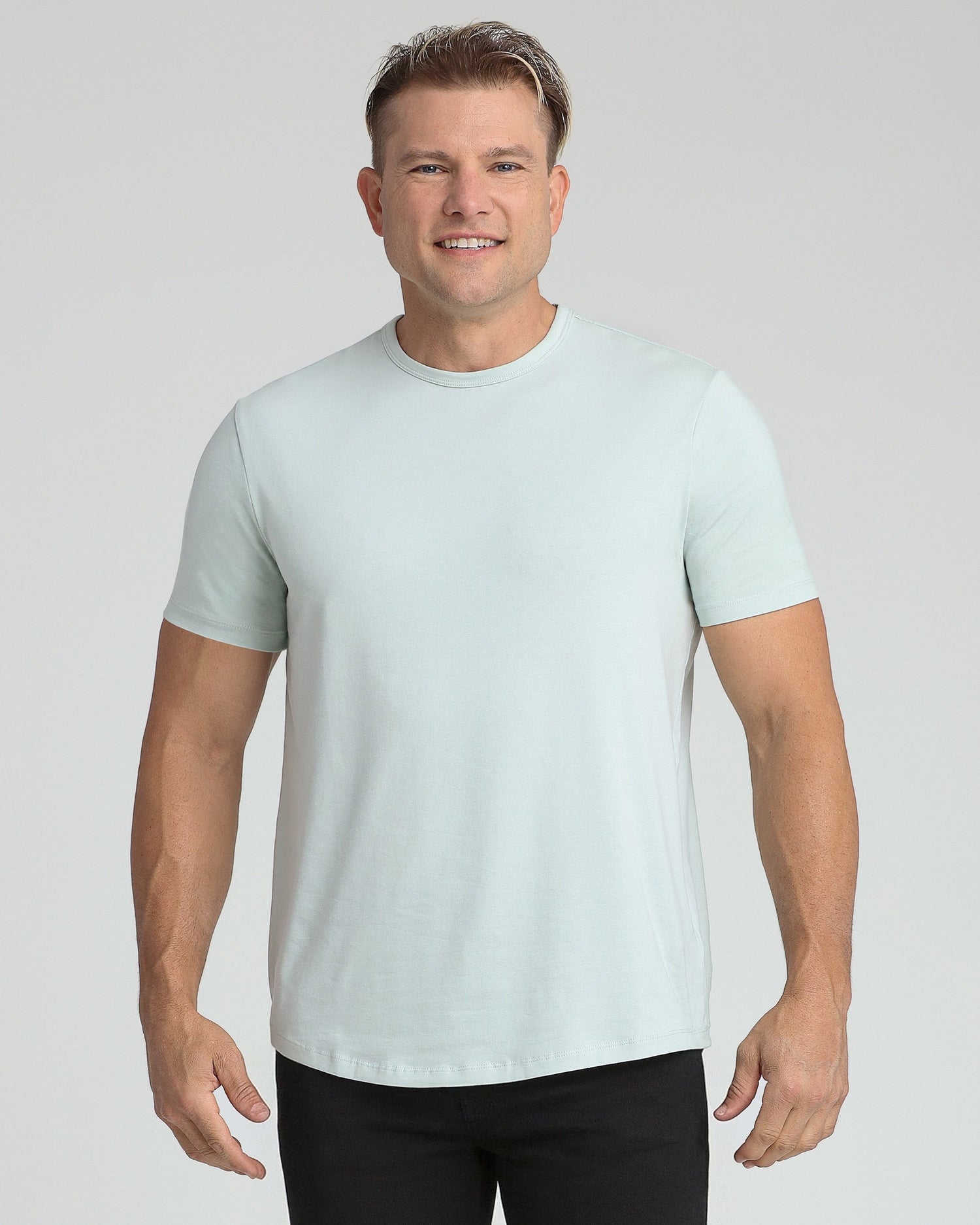 Man wearing light blue crew neck short-sleeve t-shirt with black pants.