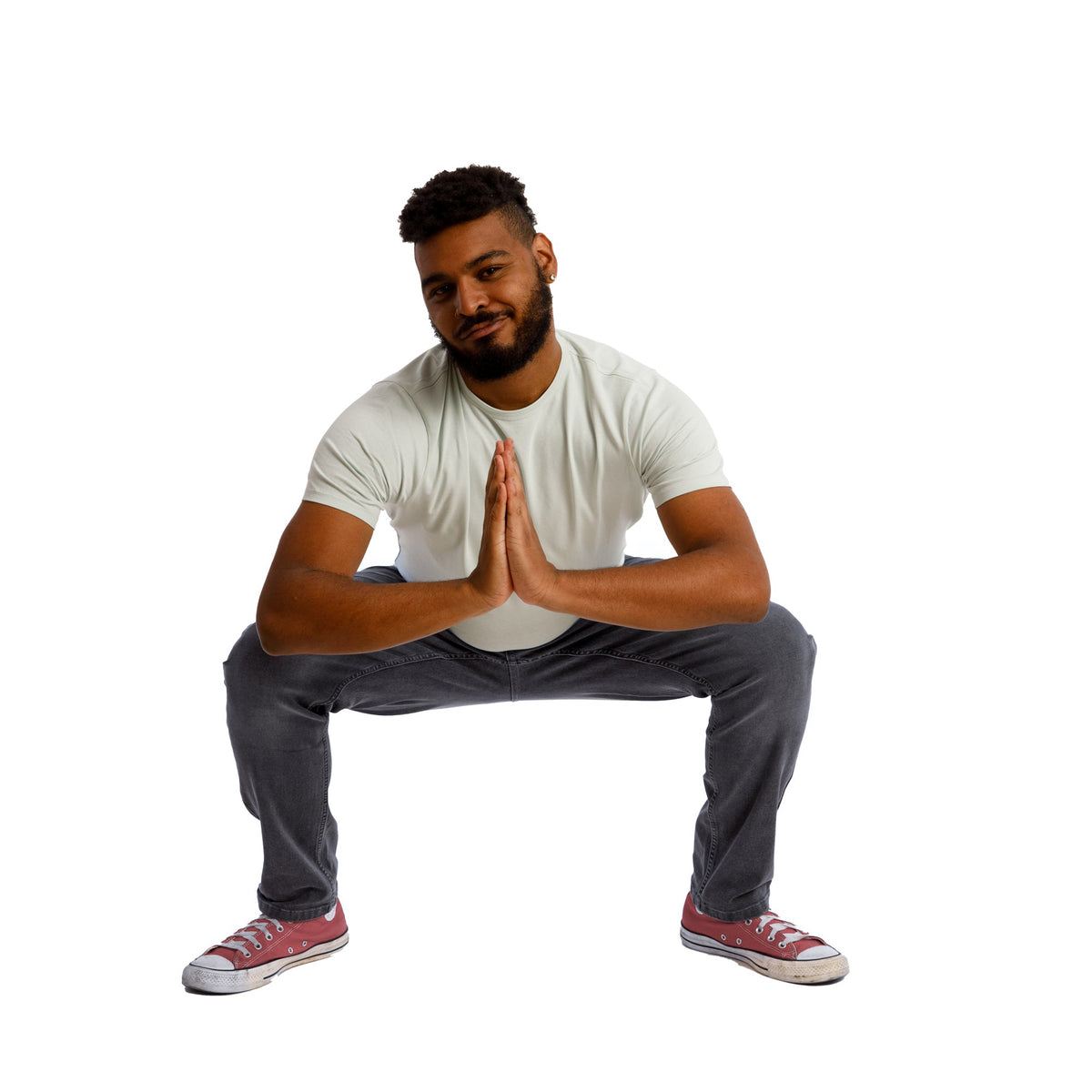 Man wearing gray short-sleeve t-shirt and dark jeans in a crouched pose.