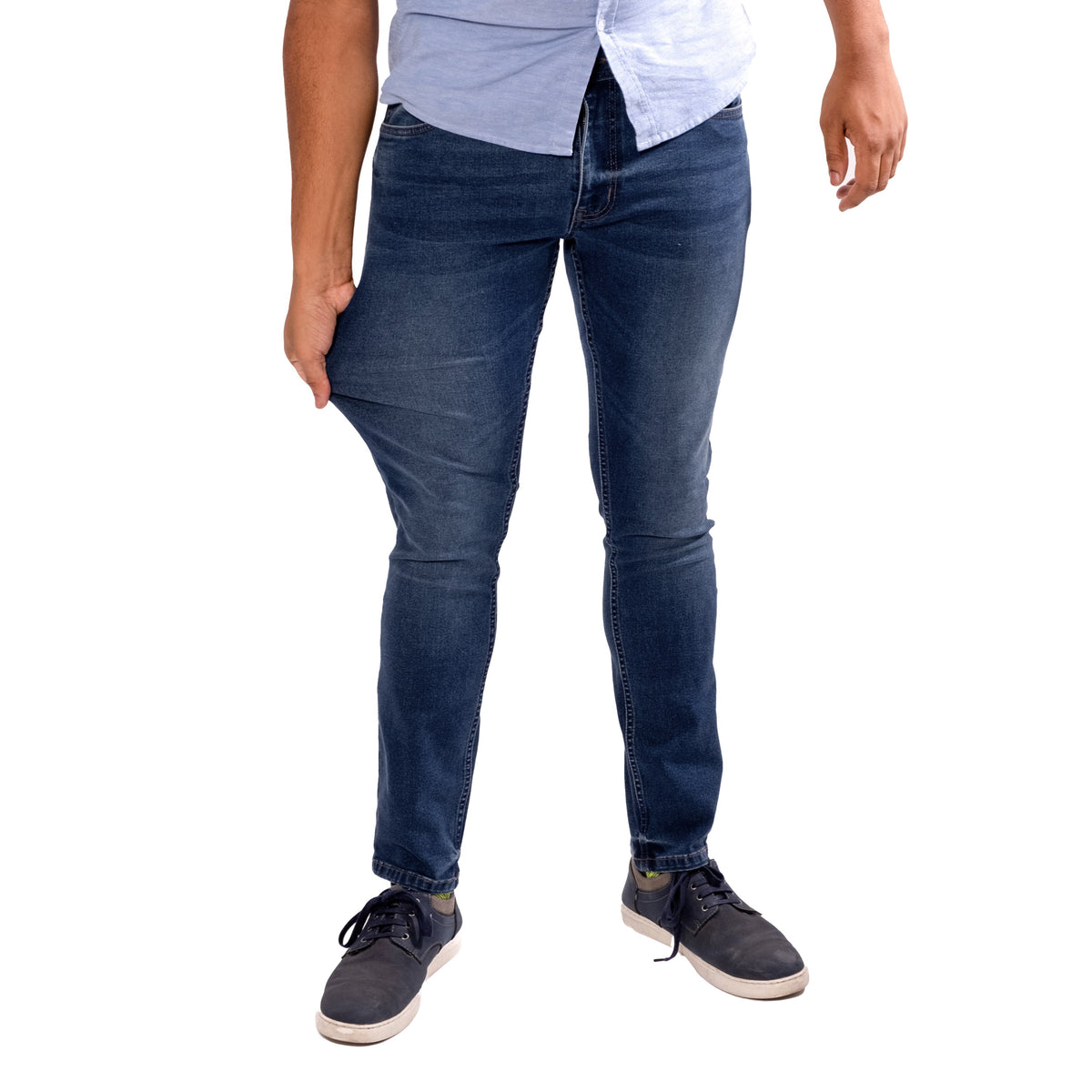 Man wearing dark blue skinny fit jeans with light blue and white layered shirts and dark sneakers.