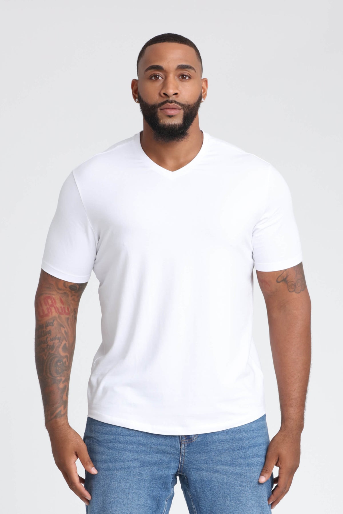 White v-neck short-sleeve t-shirt on a man wearing blue jeans.