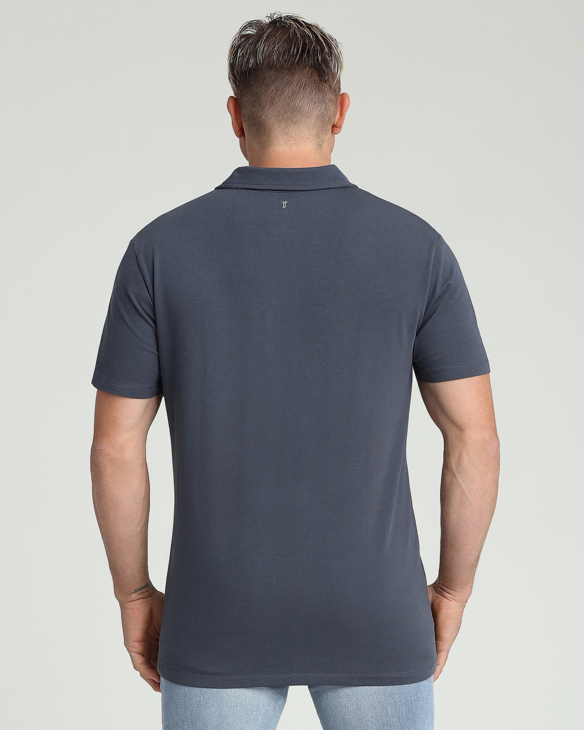 Steel-colored polo shirt with short sleeves and collar, shown from back on a model wearing light blue jeans.