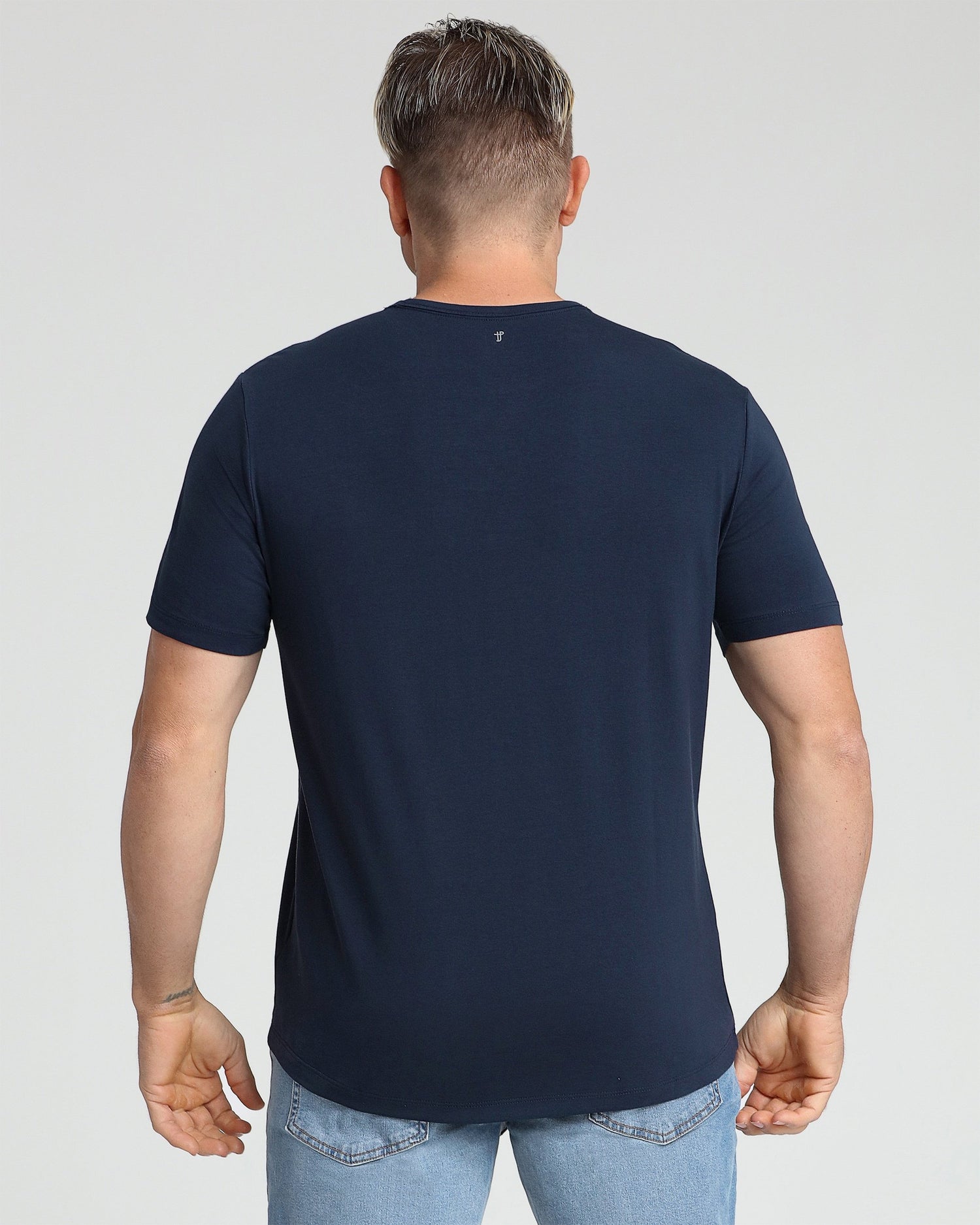 Man wearing navy crew neck t-shirt with short sleeves, shown from back view.