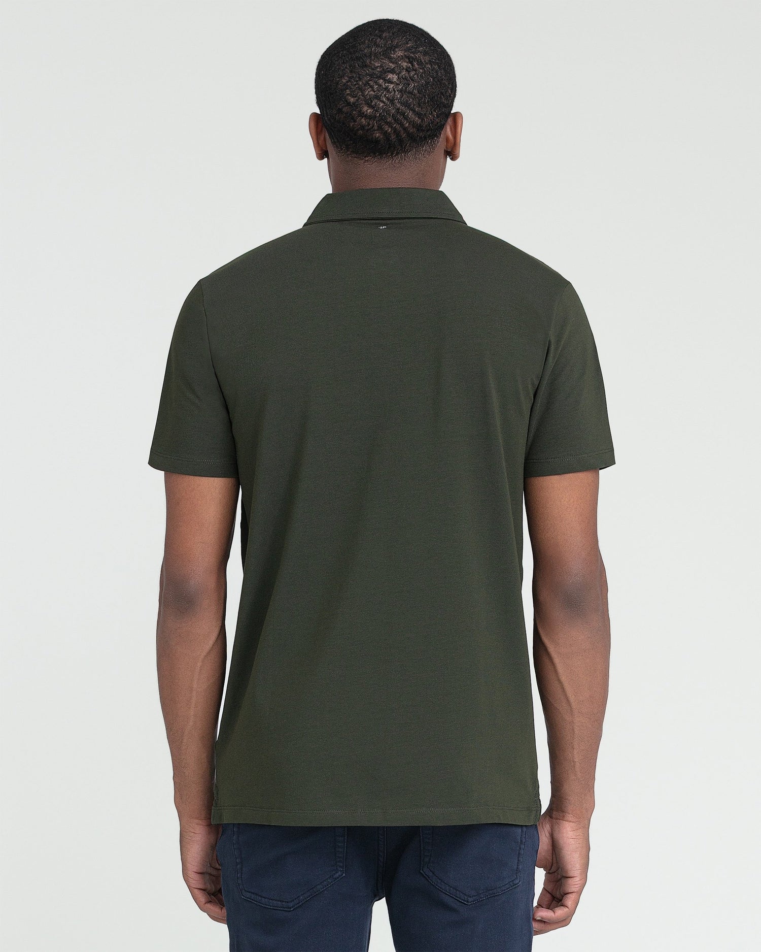 Olive polo shirt with short sleeves and collar, shown from back view on model wearing dark jeans.