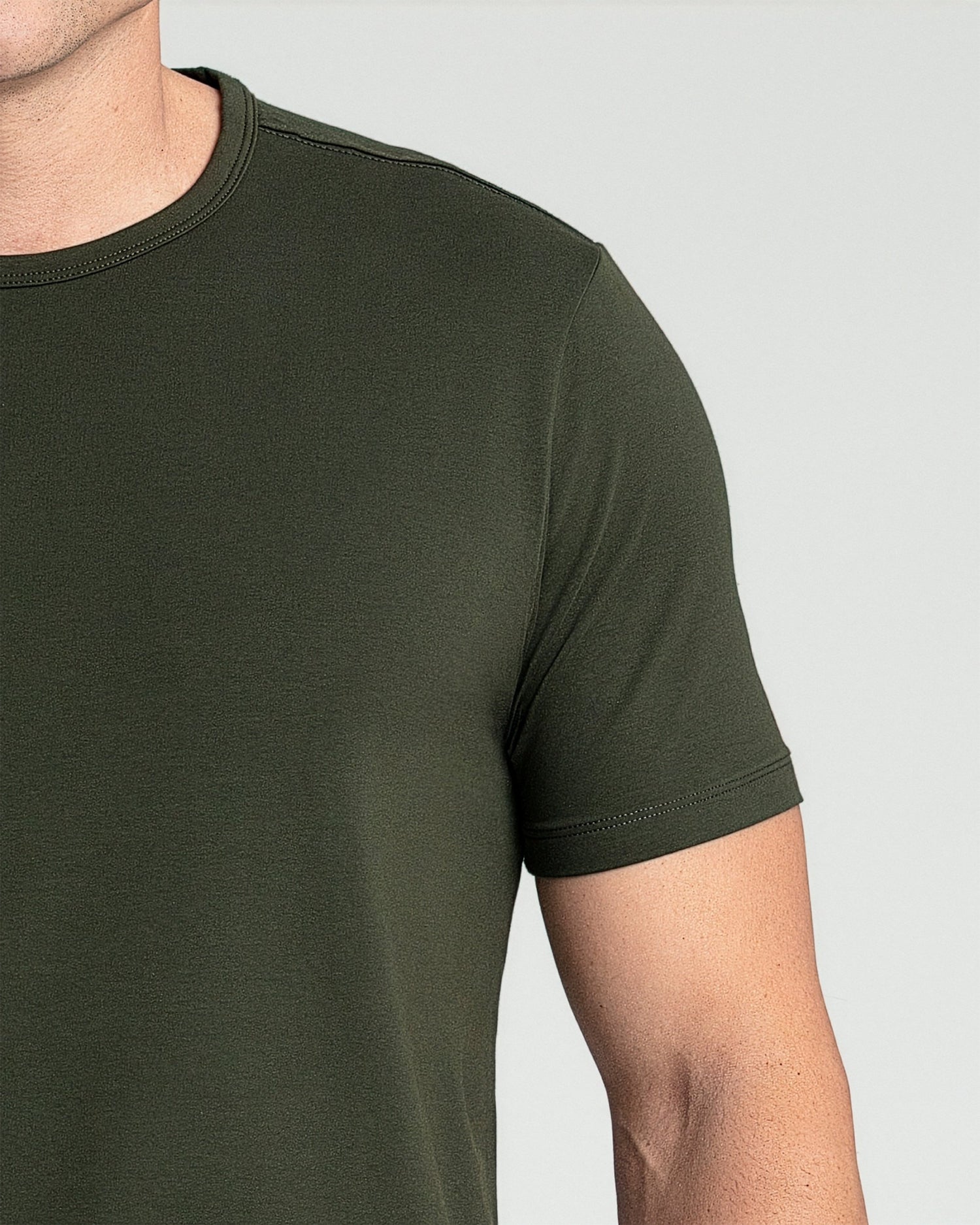 Olive green crew neck t-shirt with short sleeves worn by a person shown from shoulder to mid-torso.