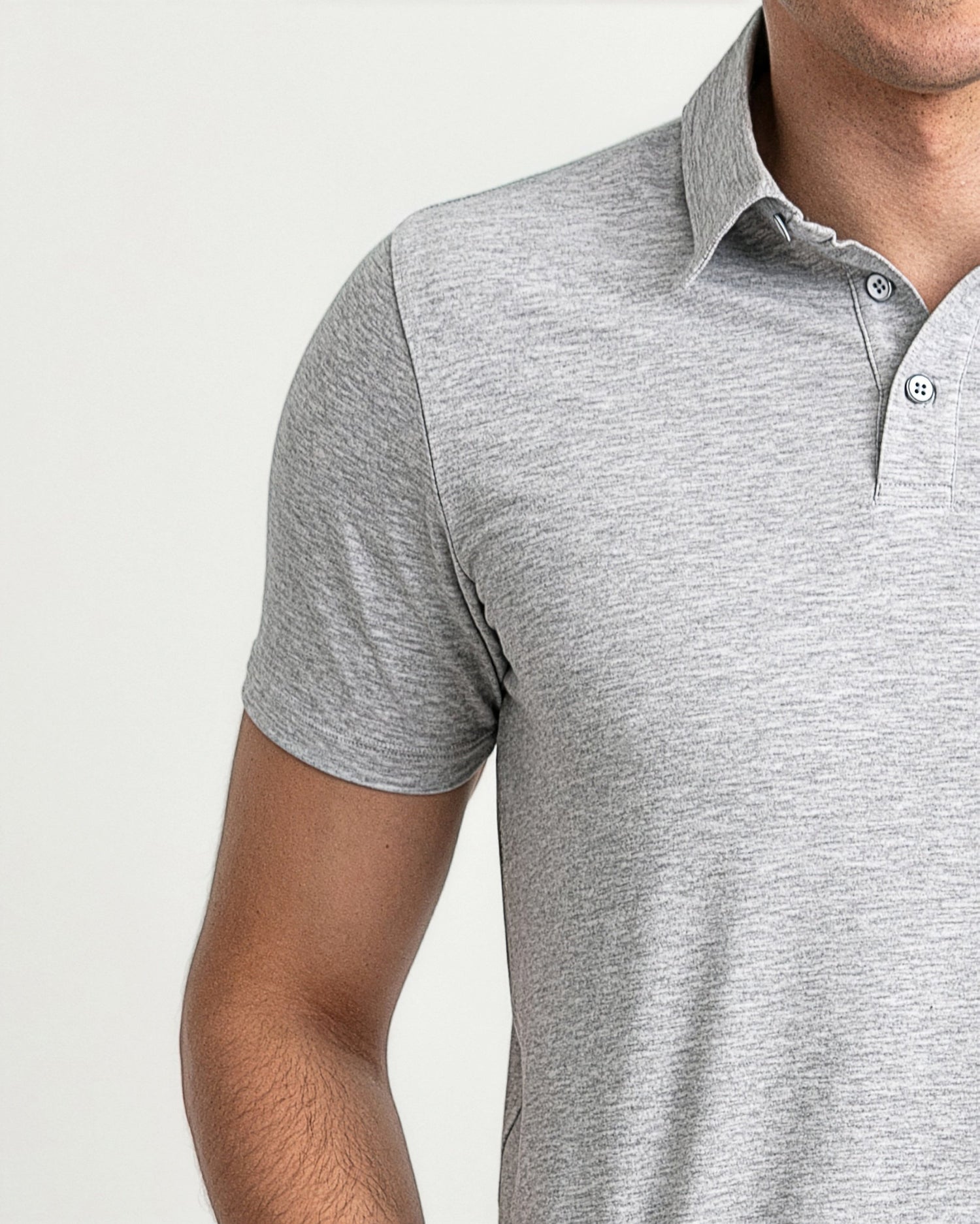 Heather grey polo shirt with white collar and button placket worn by man.