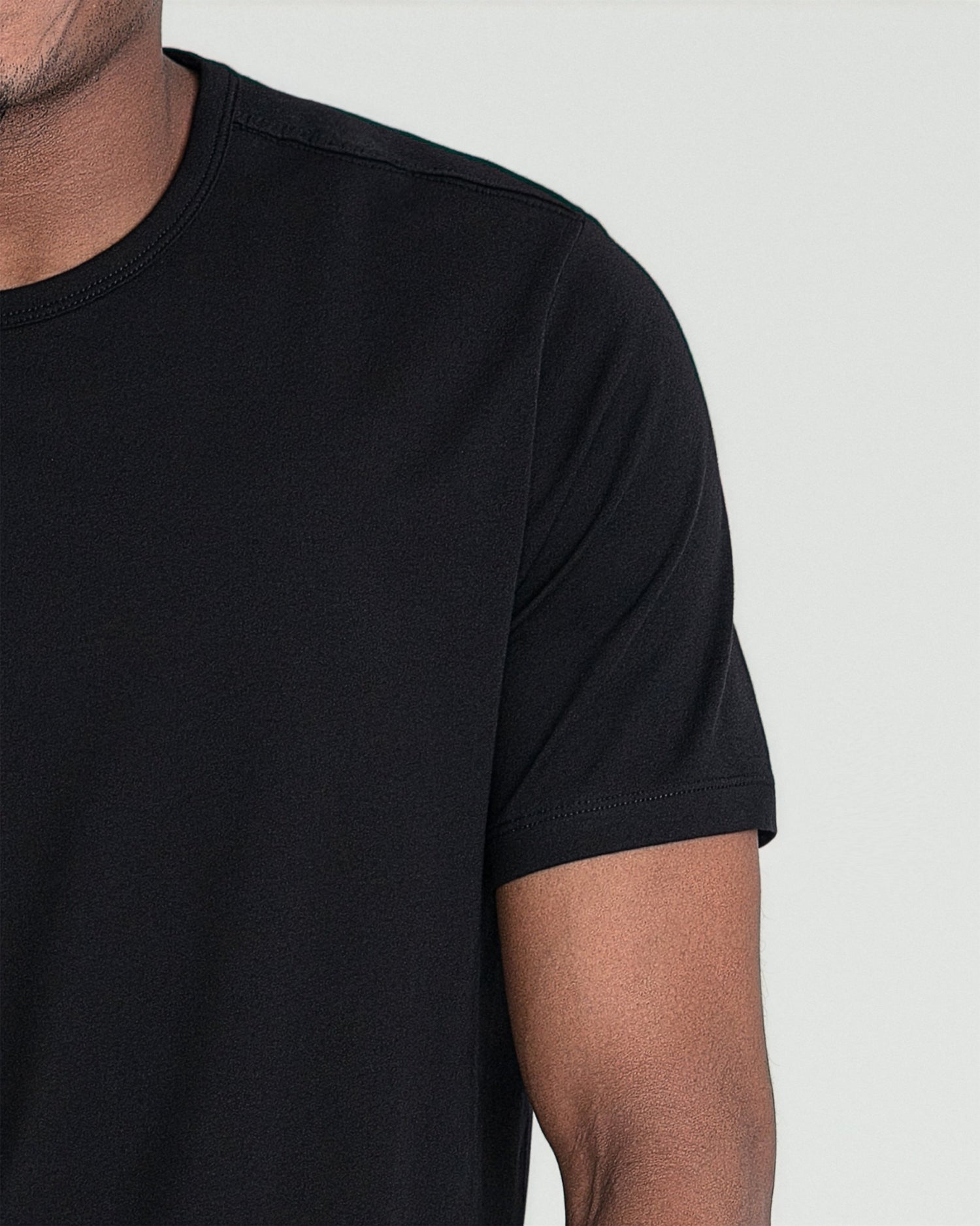 Black crew neck t-shirt with short sleeves on a model shown from shoulder to mid-chest.