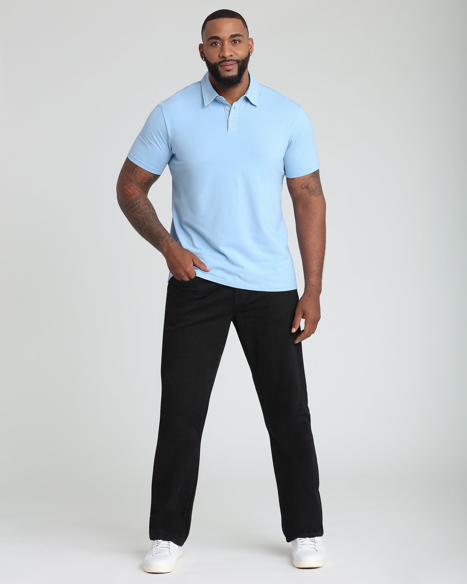 Man wearing light blue short-sleeve polo shirt with collar and button placket, paired with black pants.