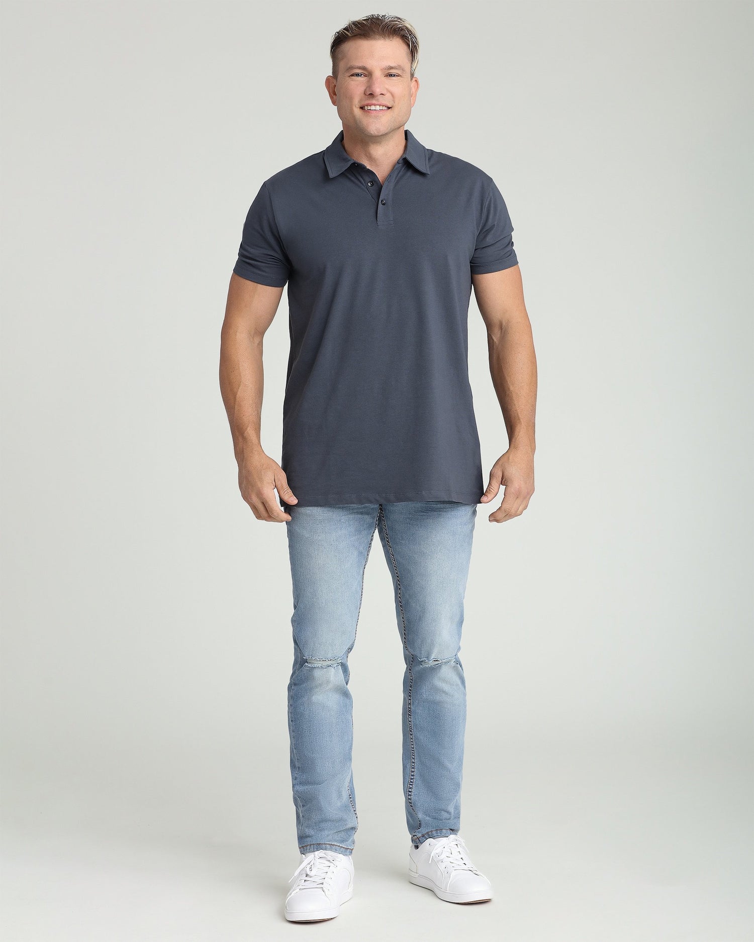Man wearing steel gray short-sleeve polo shirt with collar and button placket paired with light blue jeans.