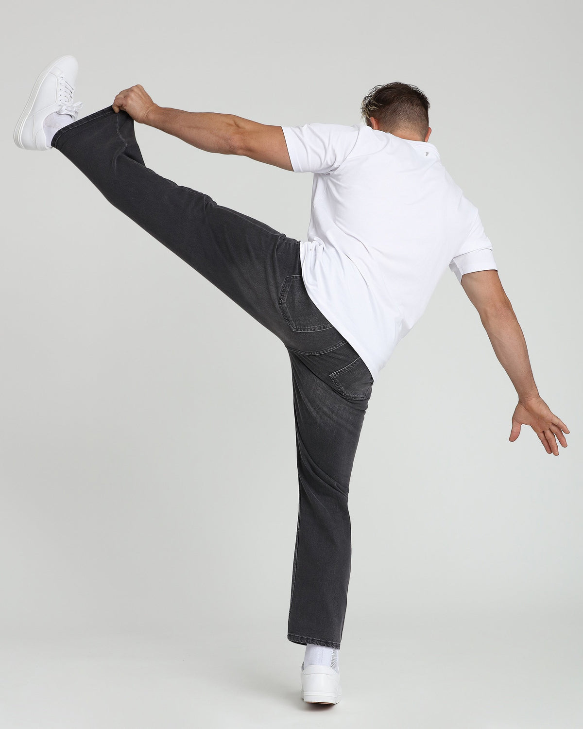 White crew neck t-shirt with short sleeves worn with dark jeans and white sneakers.