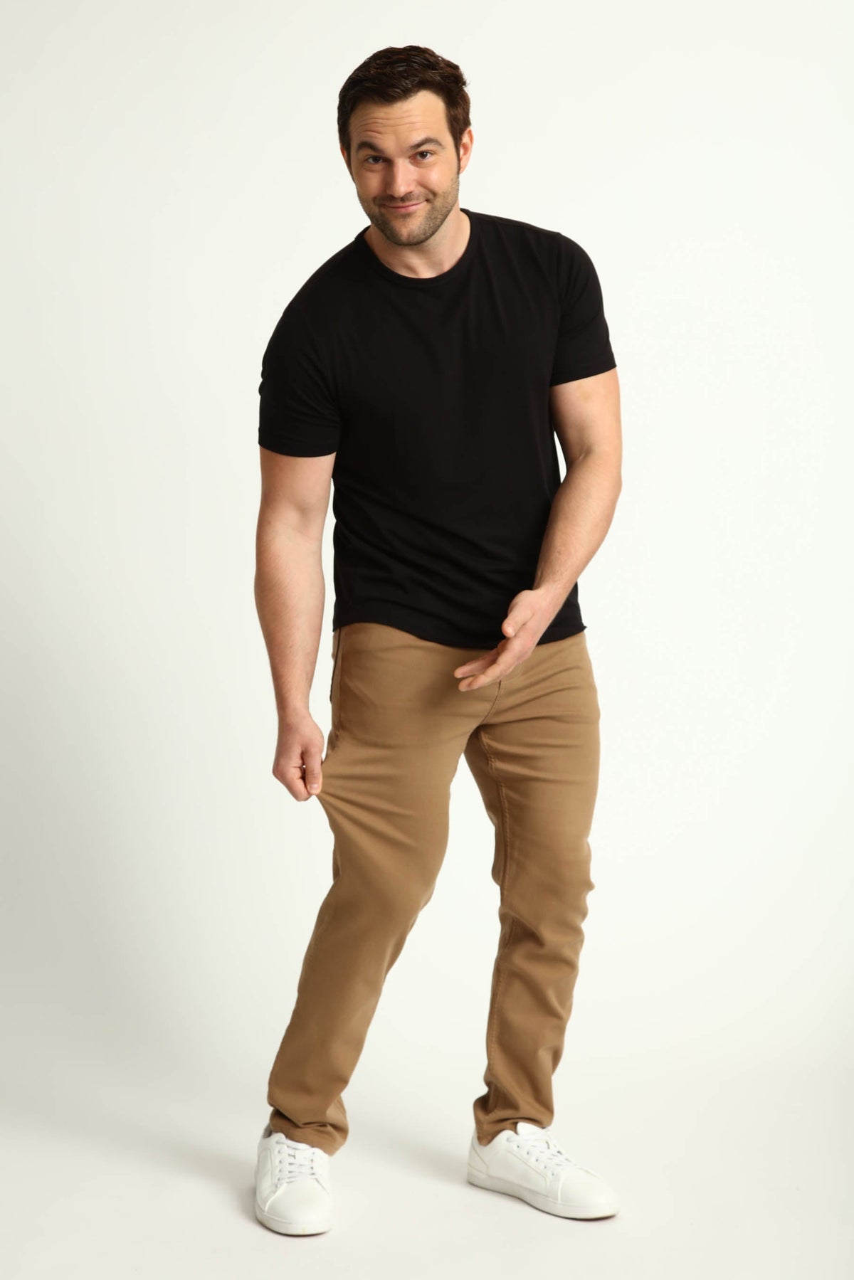 Man wearing black short-sleeve t-shirt and dark khaki slim fit pants with white sneakers.