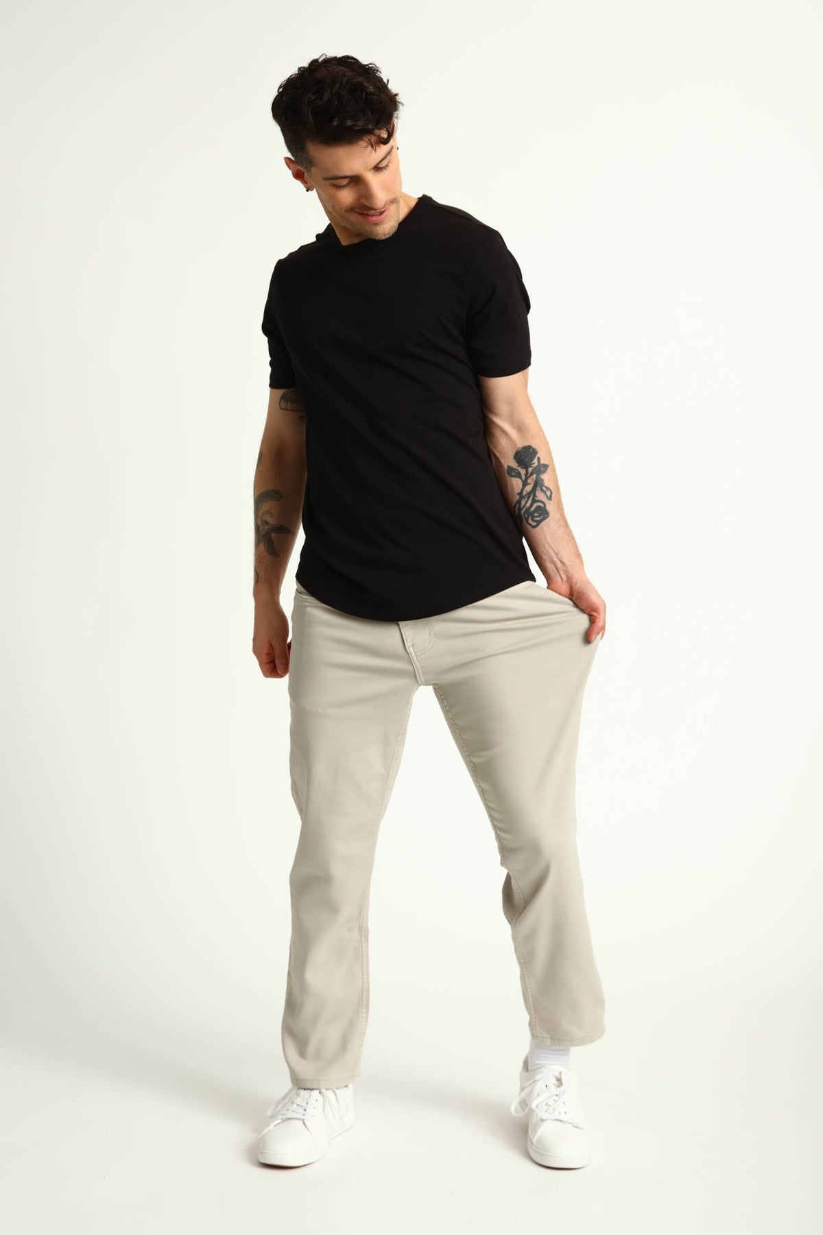 Man wearing black short-sleeve t-shirt and light grey athletic fit chinos with white sneakers.