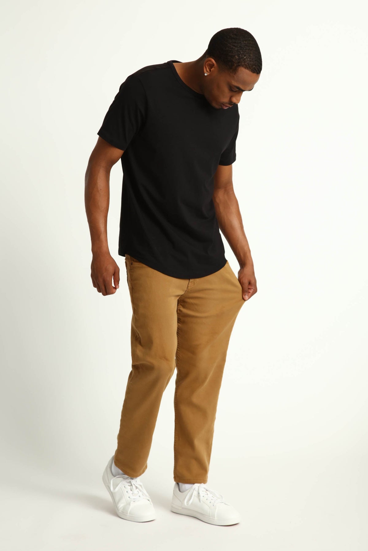 Man wearing black short-sleeve t-shirt and tobacco brown slim fit pants with white sneakers.