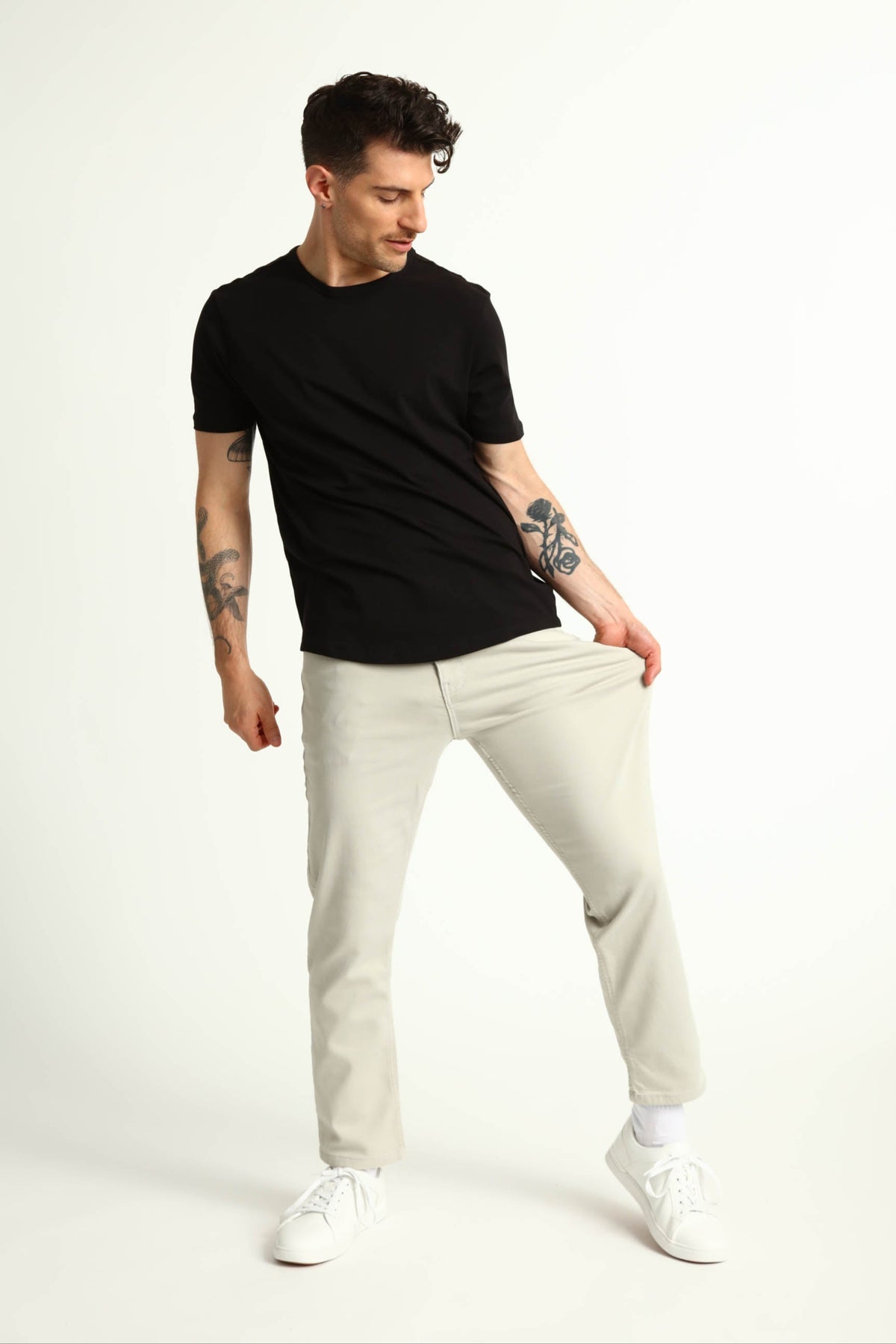 Man wearing black short-sleeve t-shirt and light grey slim fit pants with white sneakers.