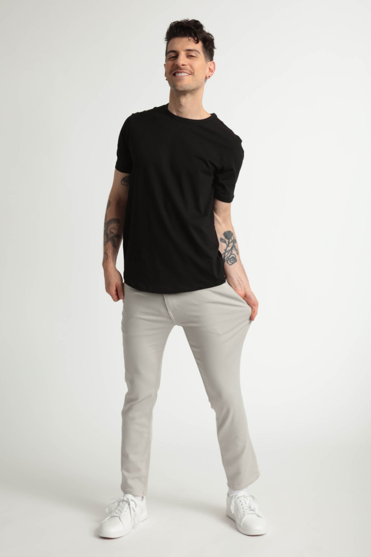 Man wearing black short-sleeve t-shirt and light grey slim fit pants with white sneakers.