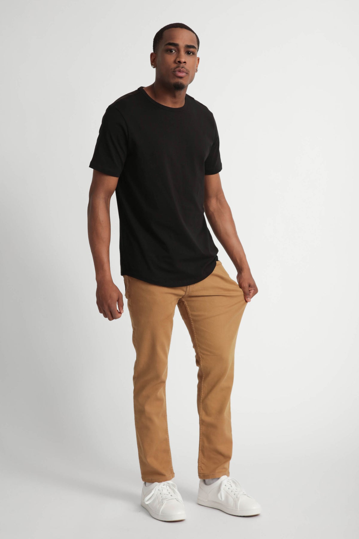 Man wearing black short-sleeve t-shirt and tobacco brown slim fit pants with white sneakers.