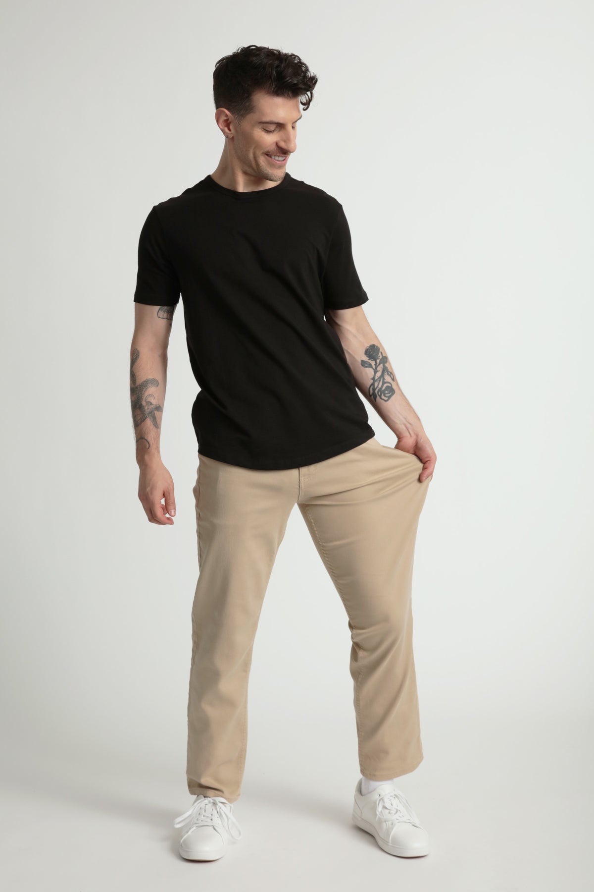 Man wearing black crew neck t-shirt and light khaki athletic fit pants with white sneakers.