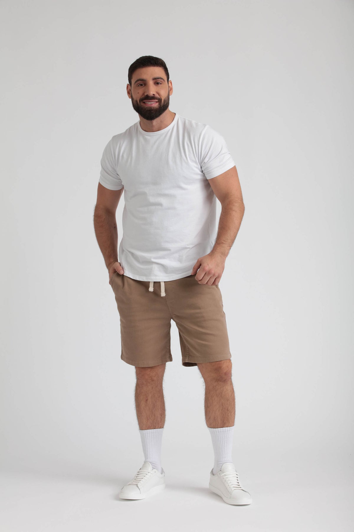 Man wearing white t-shirt and dark khaki athletic shorts with drawstring waistband.