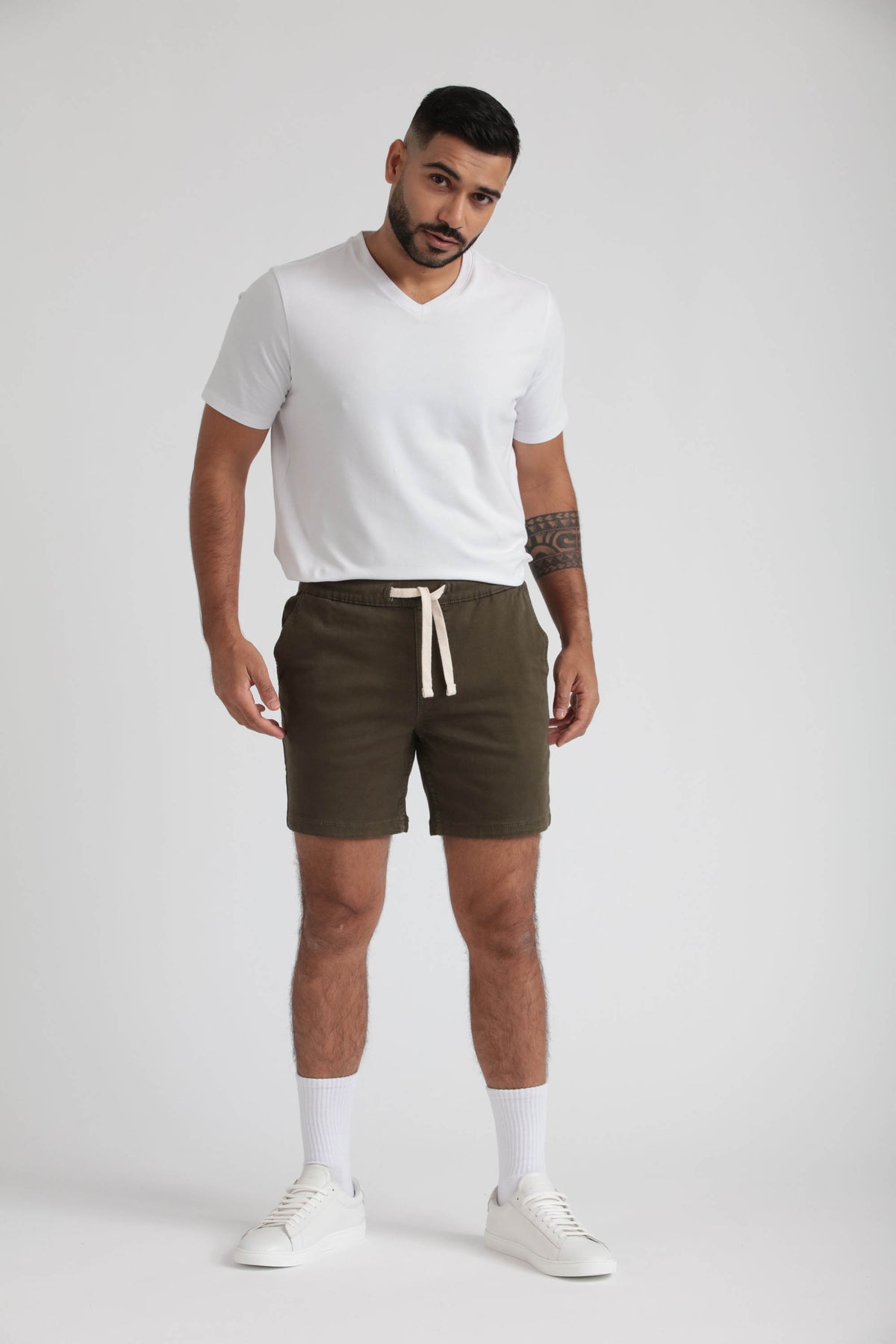 Man wearing olive green slim fit shorts with drawstring waist and white V-neck t-shirt.