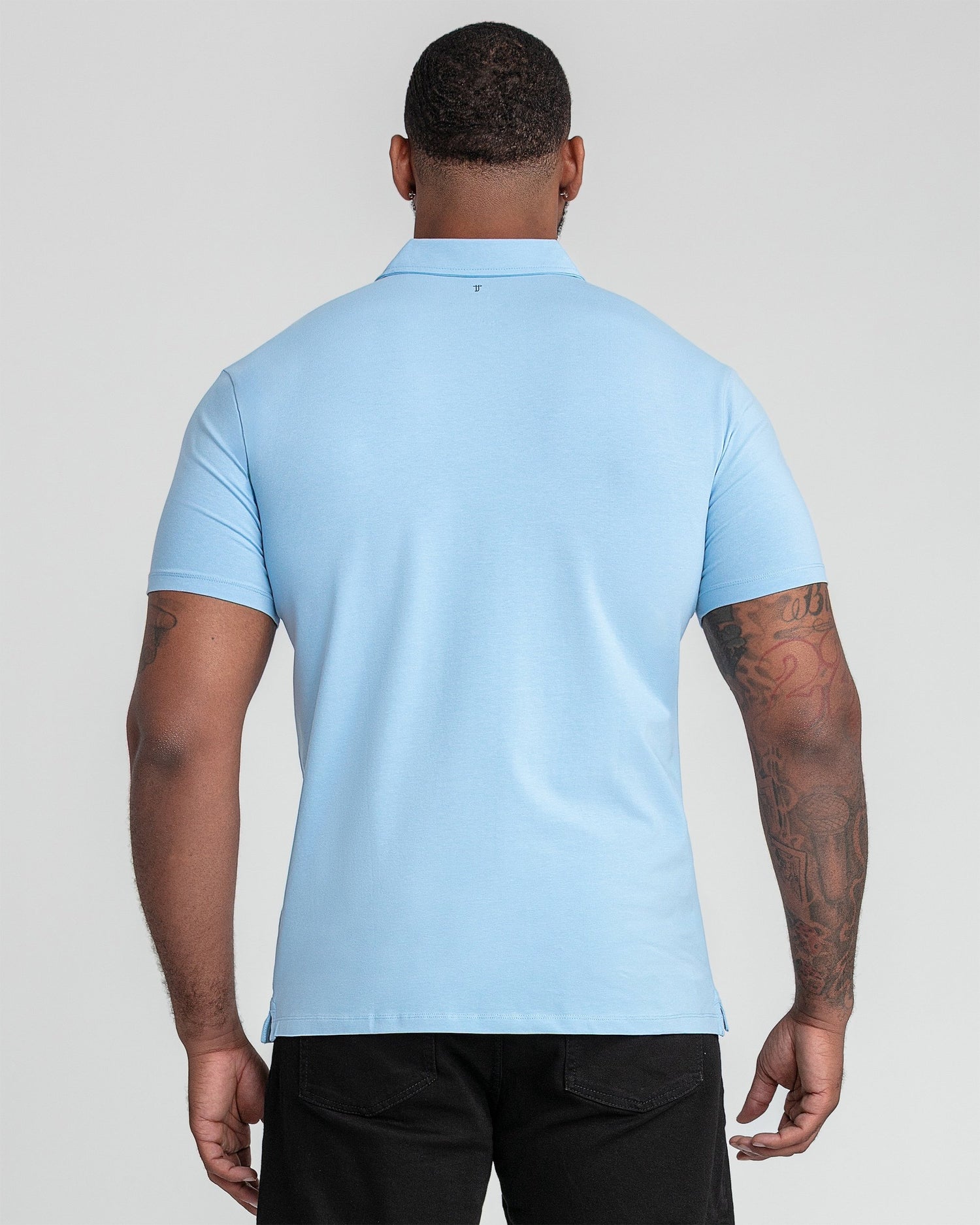Man wearing light blue polo shirt with collar, shown from back view.