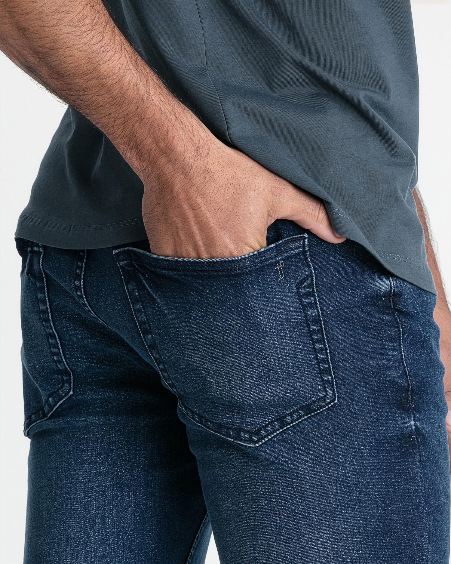 Man wearing smokey gray crew neck t-shirt tucked into dark blue jeans, showing fit at torso and waistband.