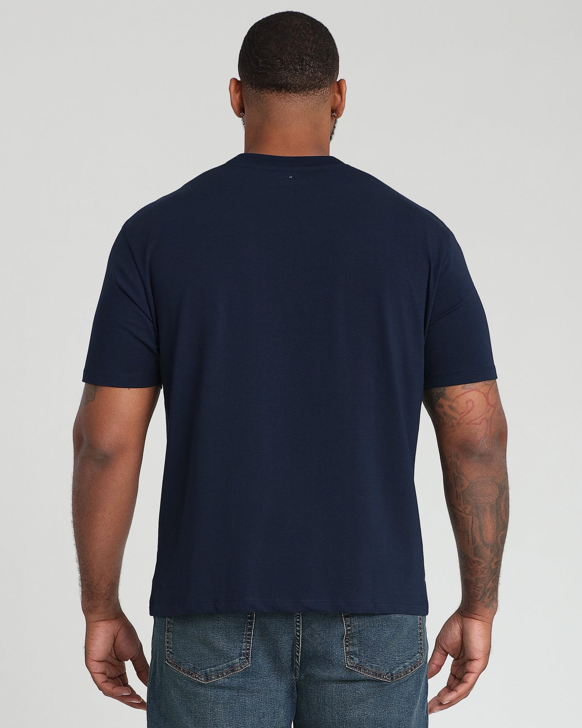 Navy crew neck t-shirt with short sleeves displayed from back on male model wearing jeans.