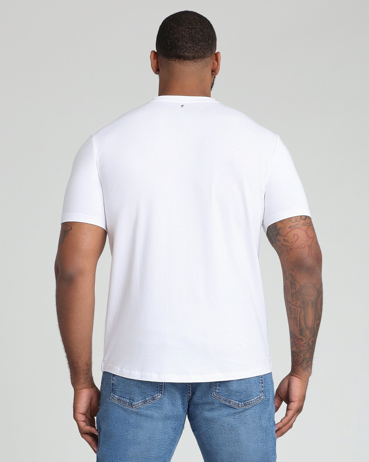 White v-neck t-shirt shown from back on model wearing blue jeans.