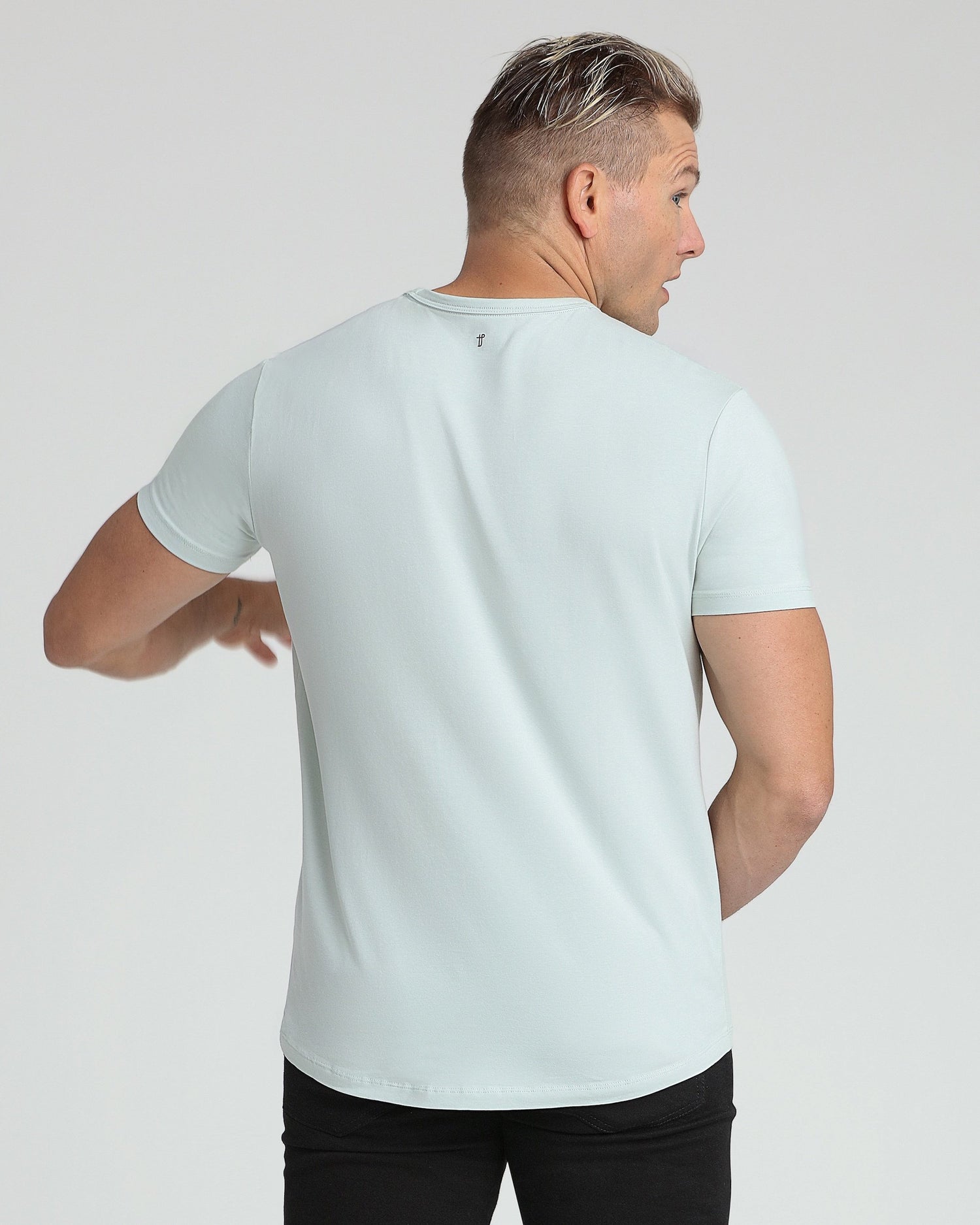 Light blue crew neck t-shirt with short sleeves, shown from back view on a model wearing black pants.