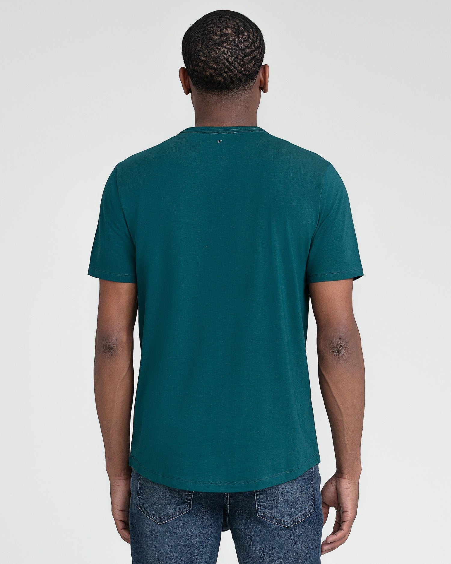 Man wearing teal crew neck short-sleeve t-shirt and blue jeans, shown from back view.