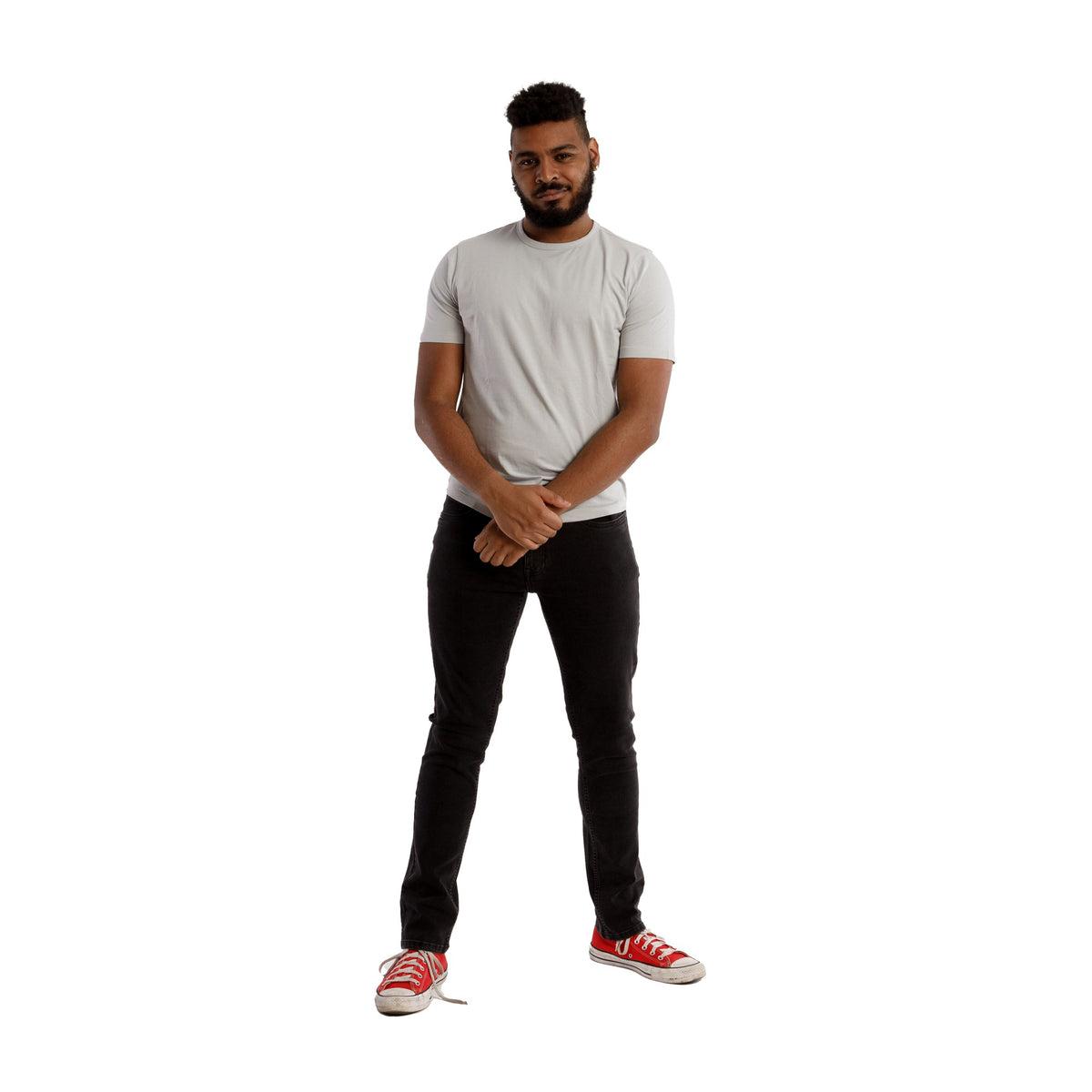 Man wearing gray short-sleeve t-shirt and faded black skinny fit jeans with red canvas sneakers.