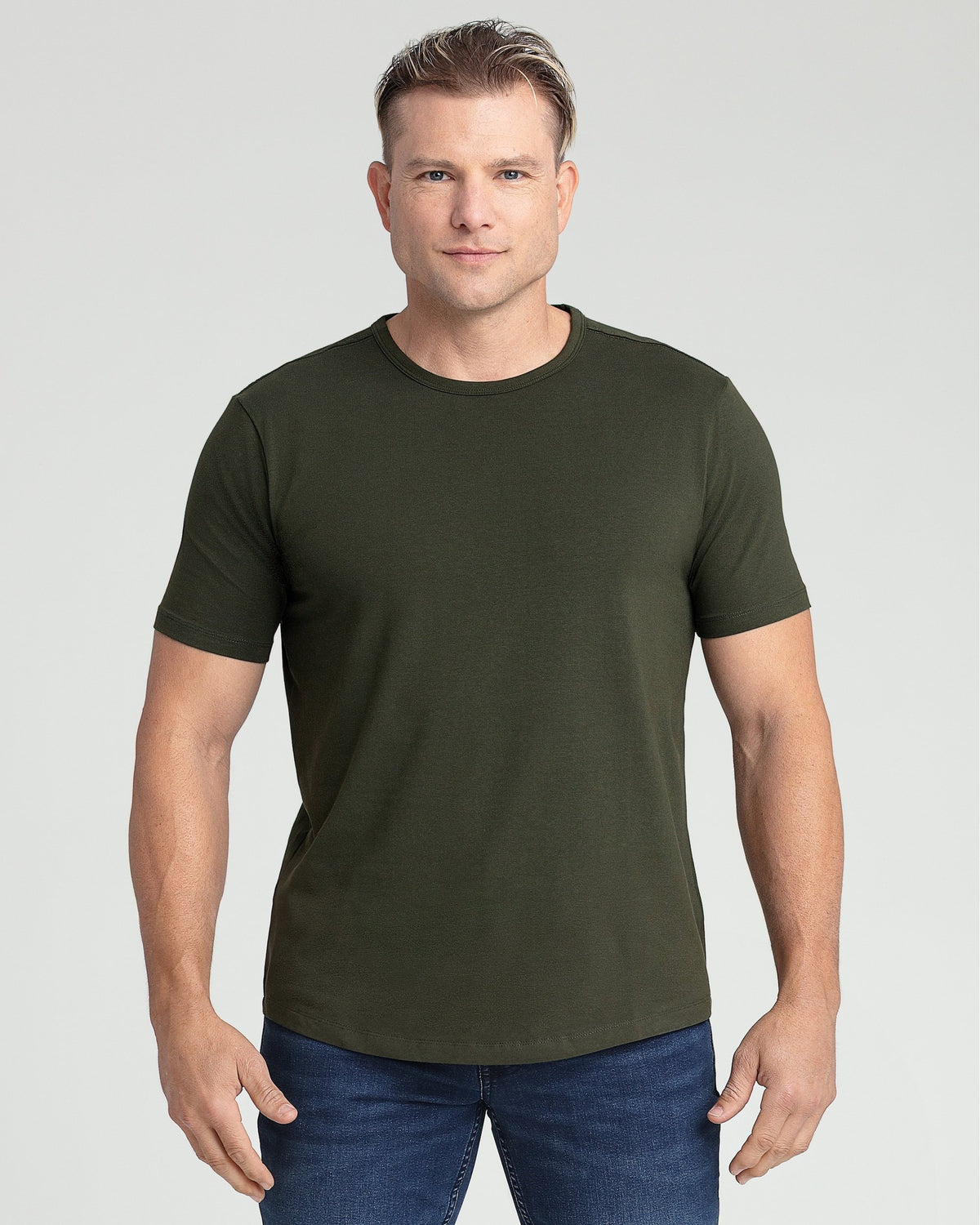 Man wearing olive green crew neck t-shirt with short sleeves and dark blue jeans.