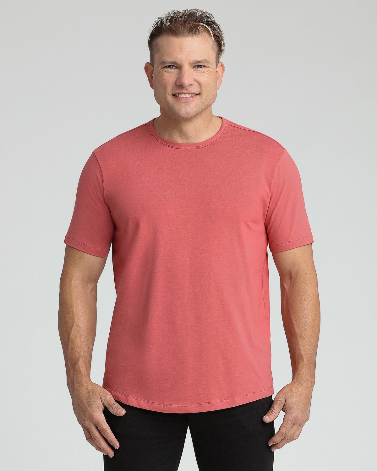 Man wearing coral crew neck t-shirt with short sleeves and black pants.