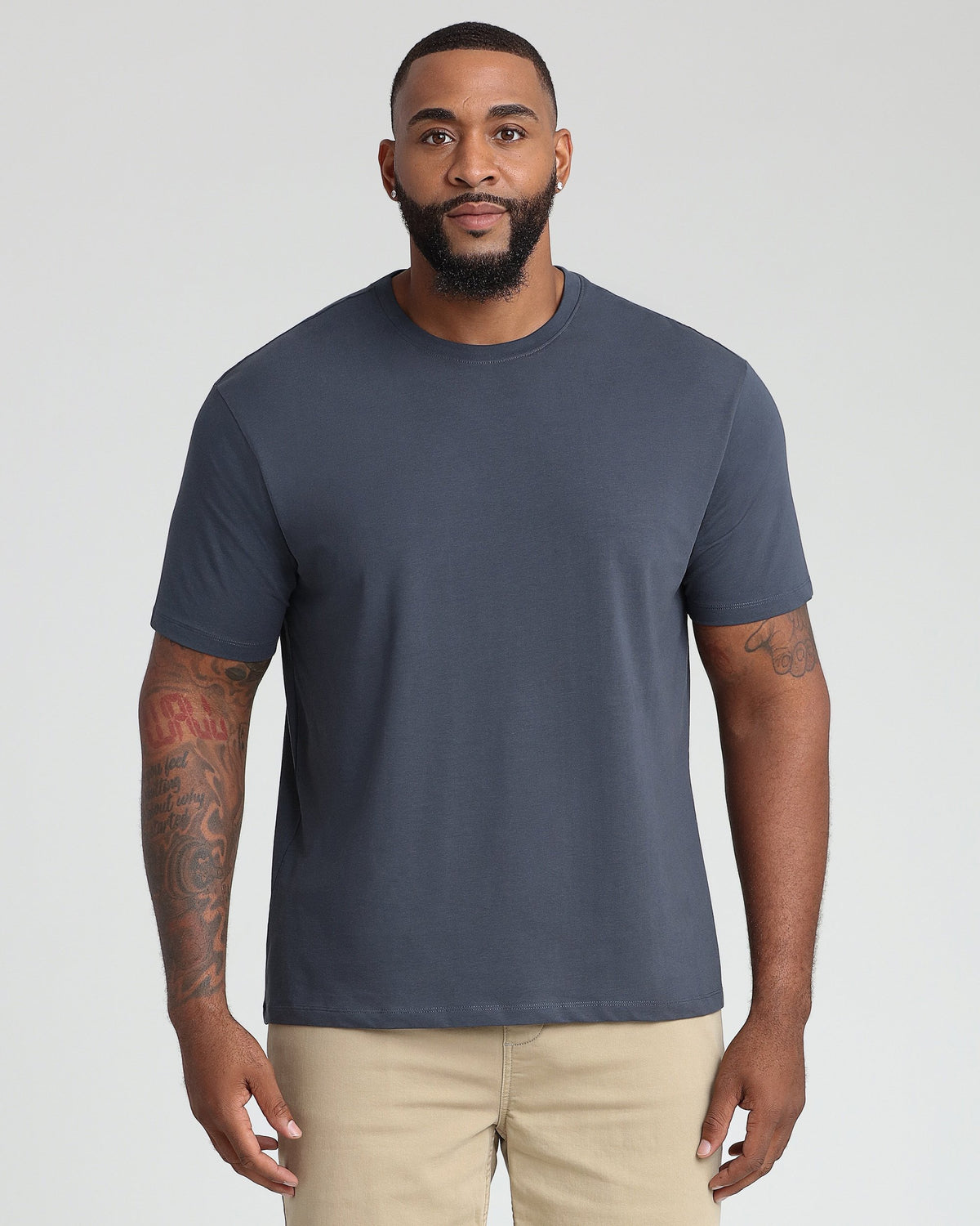 Man wearing dark blue crew neck t-shirt with khaki pants.