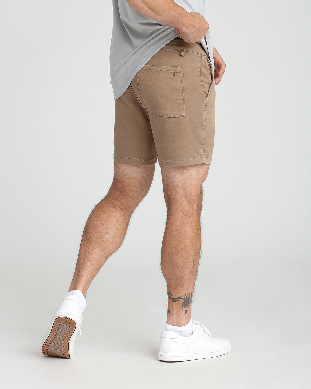 Dark khaki slim fit shorts with back pocket detail, worn with gray t-shirt and white sneakers.