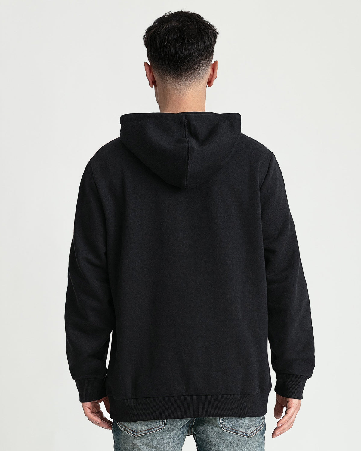Black hoodie with drawstring hood and ribbed cuffs, shown from back view on model wearing jeans.