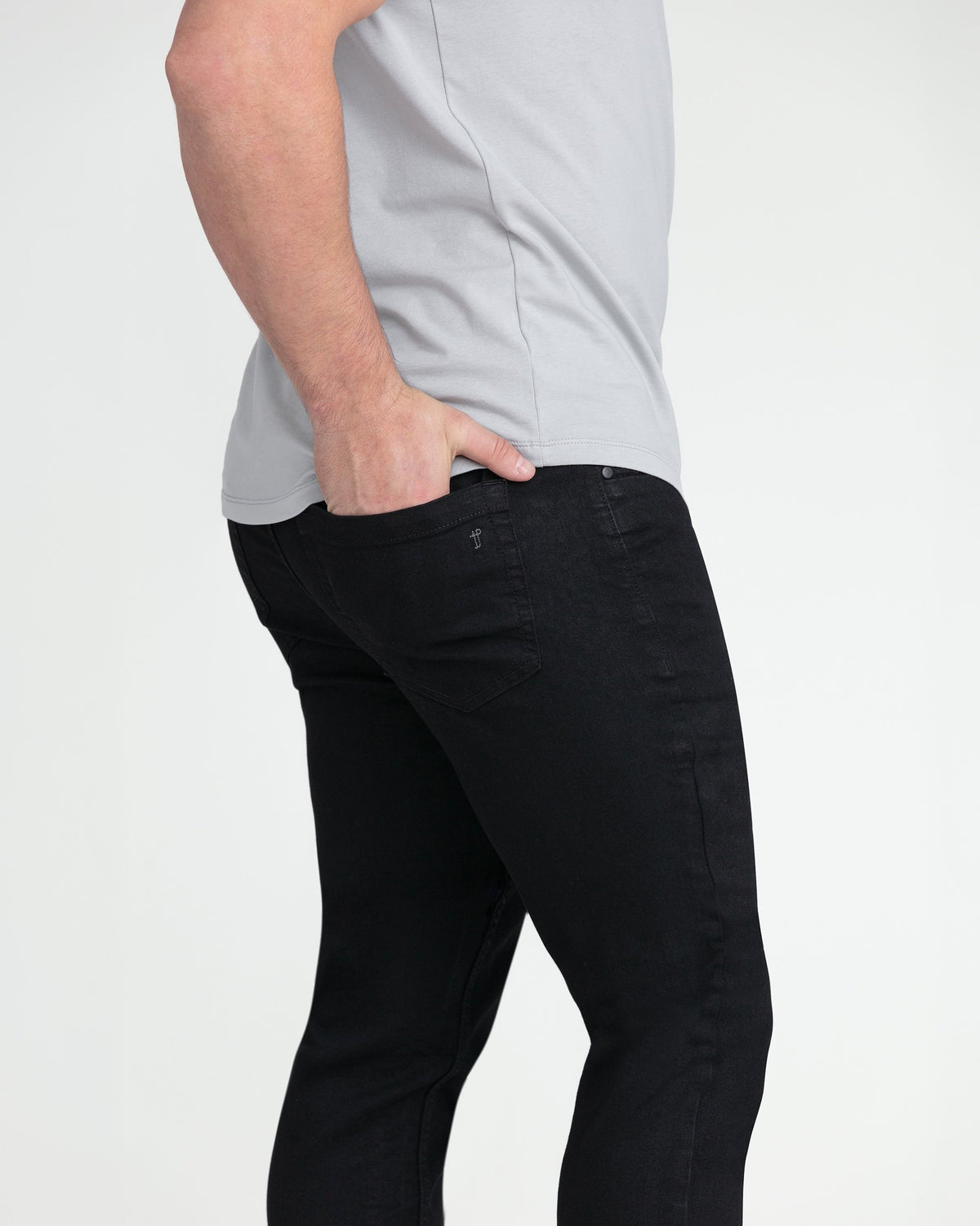 Black slim fit jeans with button fly, styled with light gray t-shirt.