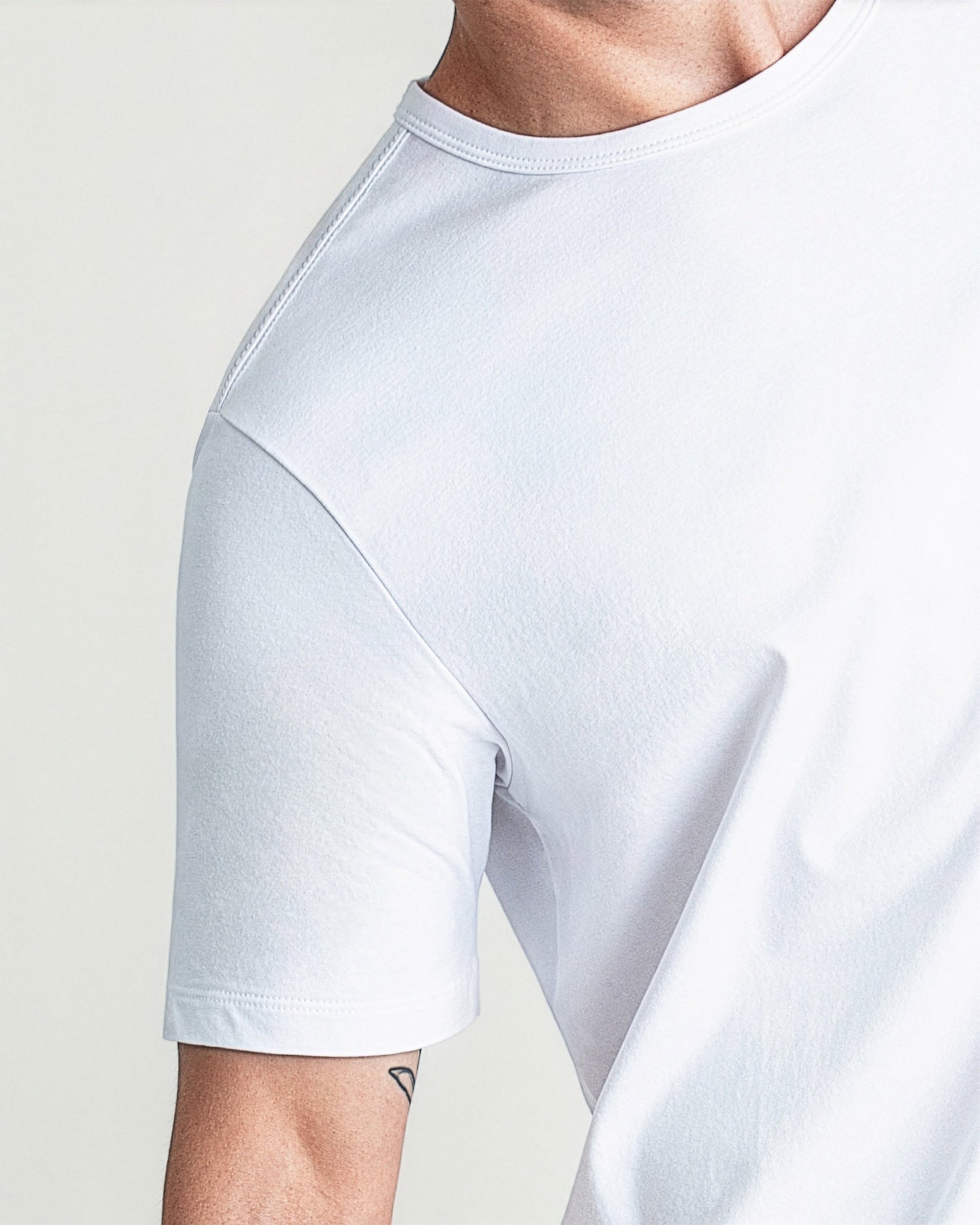 White crew neck t-shirt with short sleeves shown on male model against neutral background.