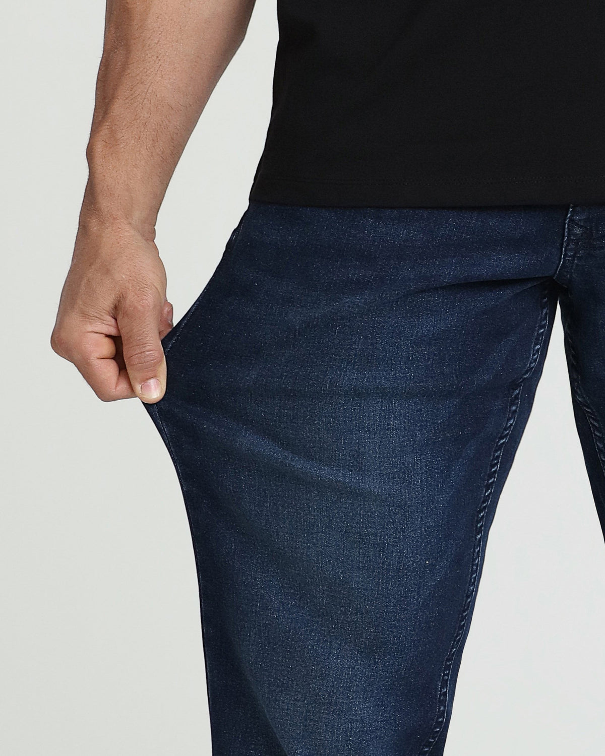 Man wearing black shirt and dark blue denim pants with relaxed thigh fit.
