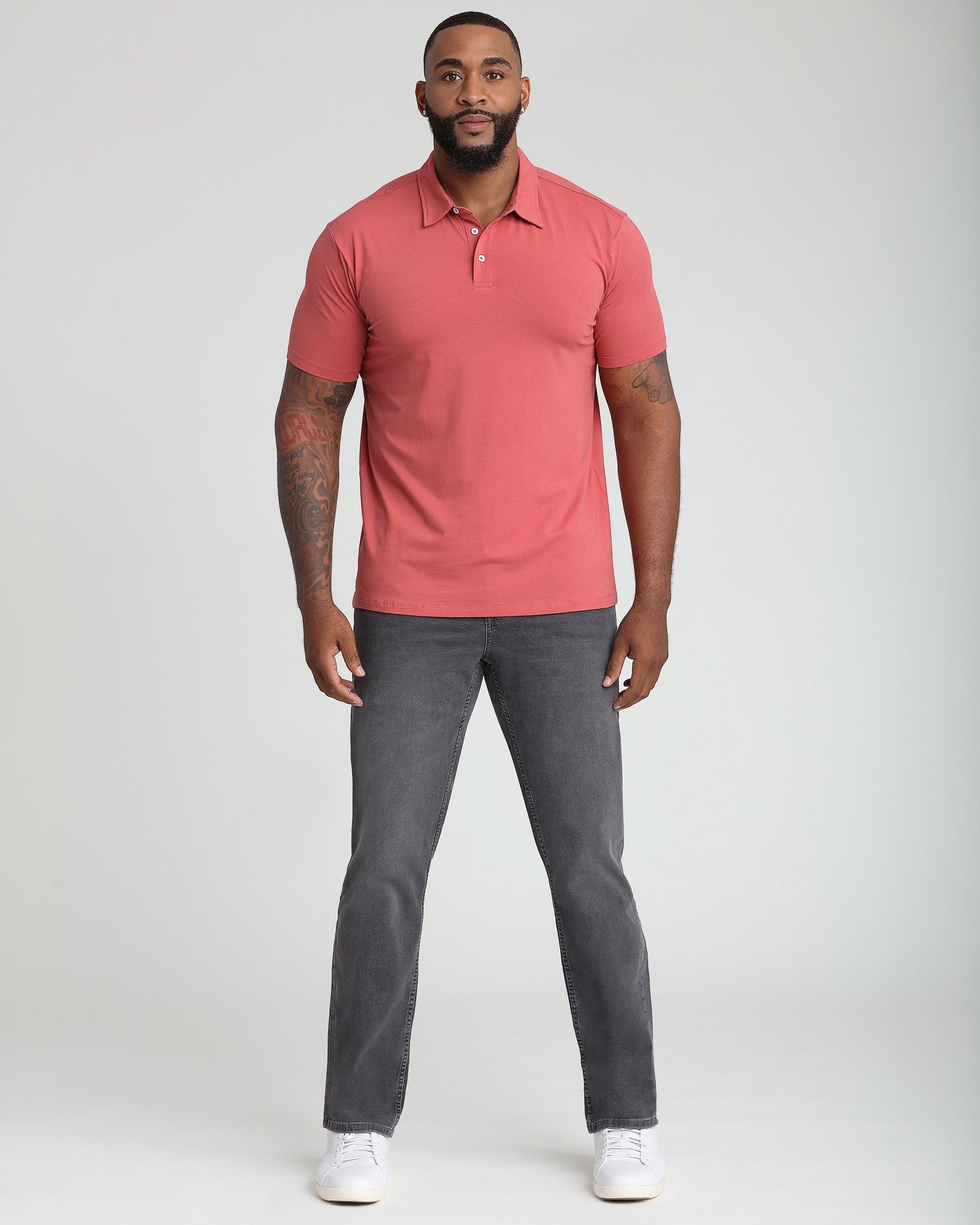 Man wearing Nantucket red polo shirt with white button placket and gray jeans.