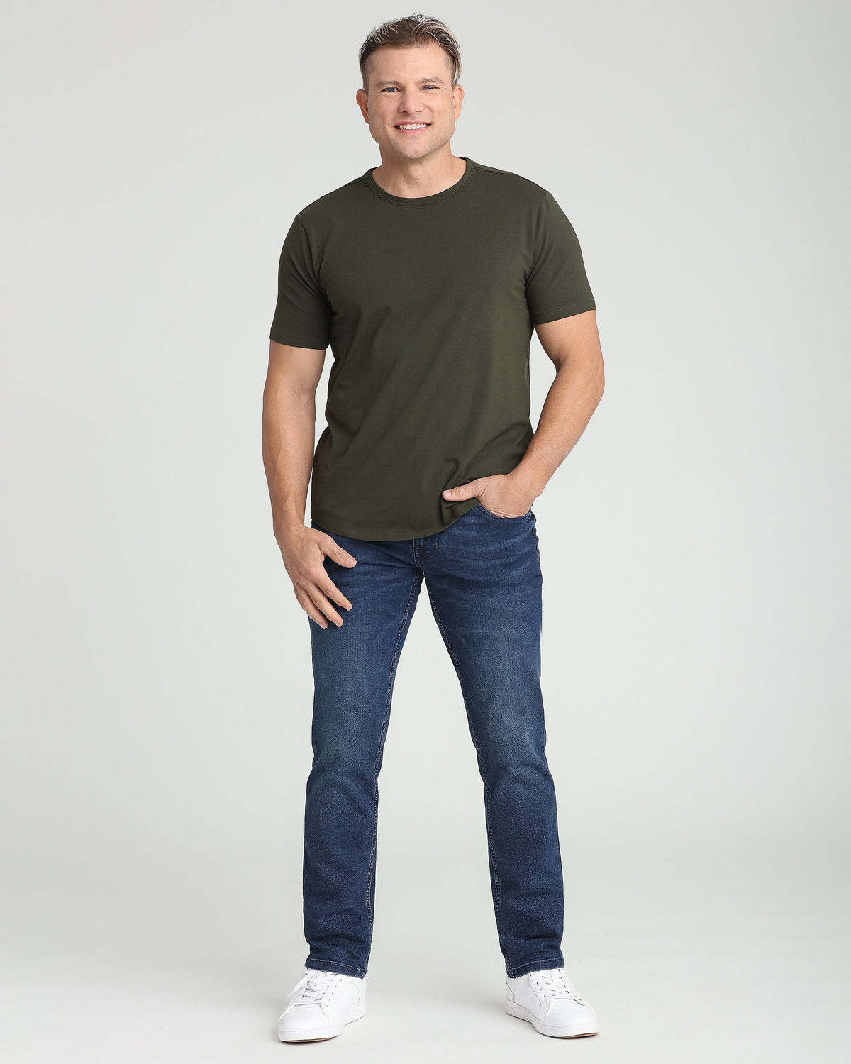 Man wearing olive crew neck t-shirt with short sleeves and dark blue jeans.