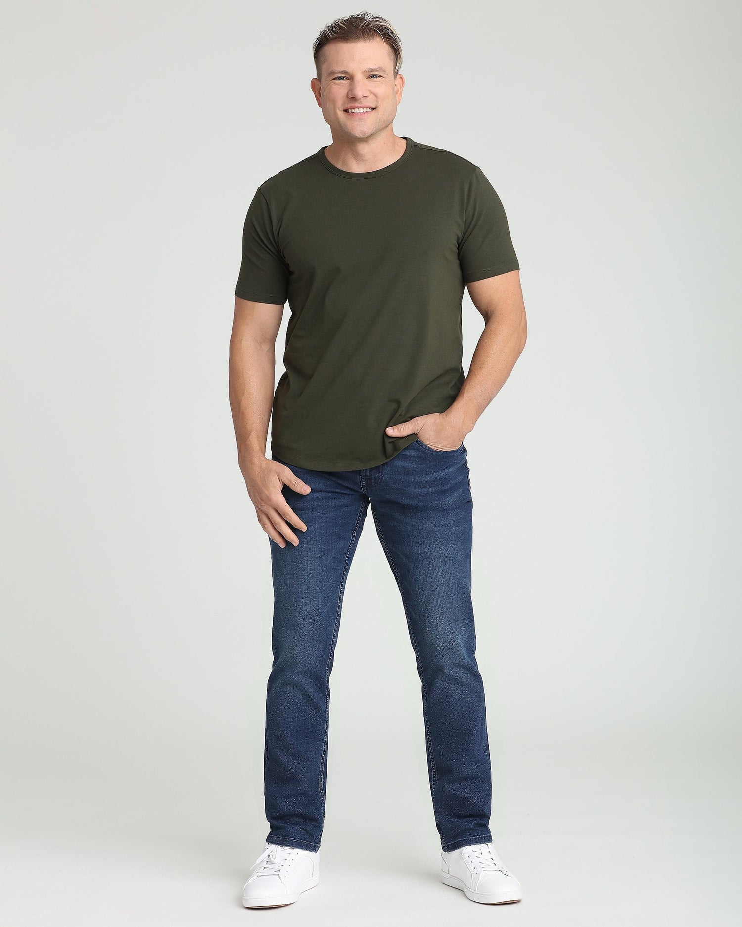 Man wearing olive crew neck t-shirt with short sleeves and dark blue jeans.
