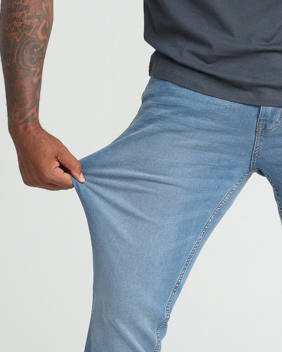 Person wearing light indigo denim jeans with a dark navy shirt, showing the fit through the thigh and hip area.