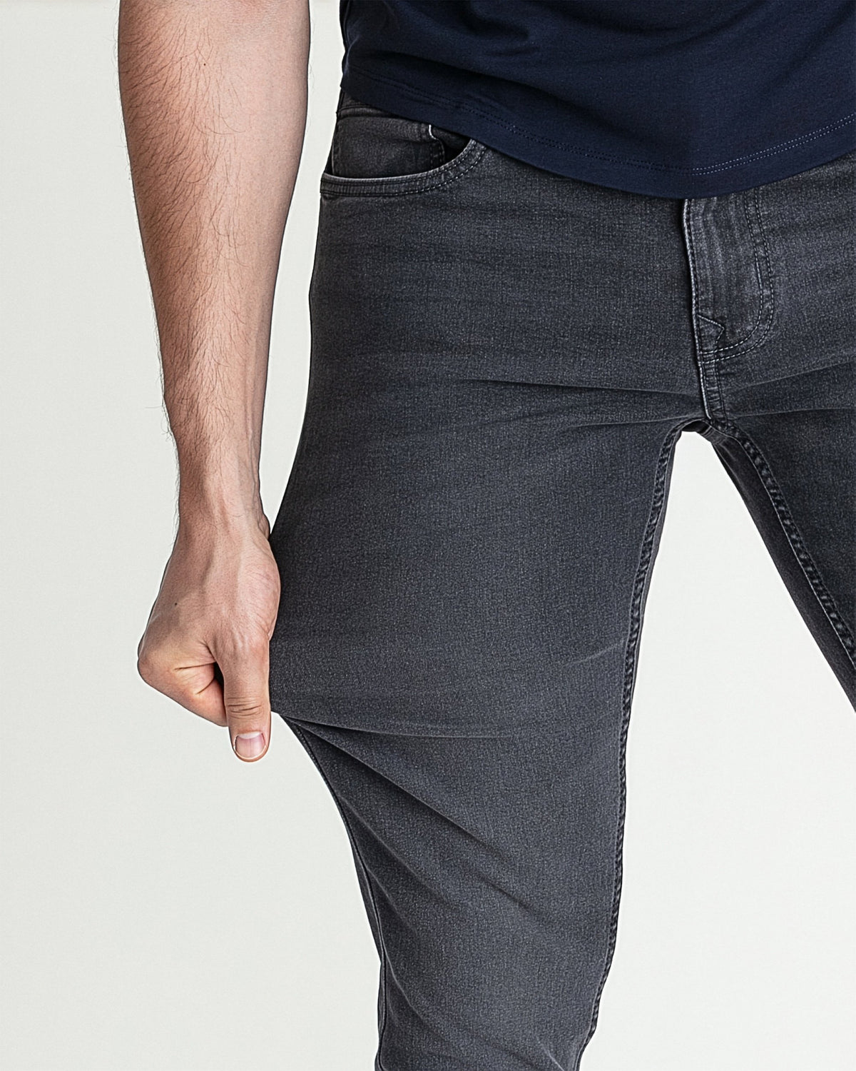 Grey skinny fit jeans on man, close-up of thigh and leg showing tapered silhouette.