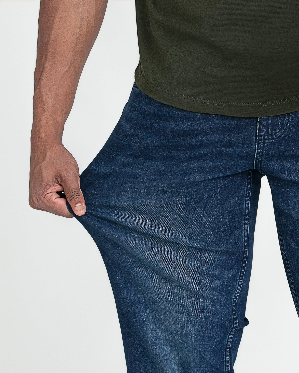 Man wearing olive green t-shirt and dark blue jeans, showing fit around torso and thigh area.