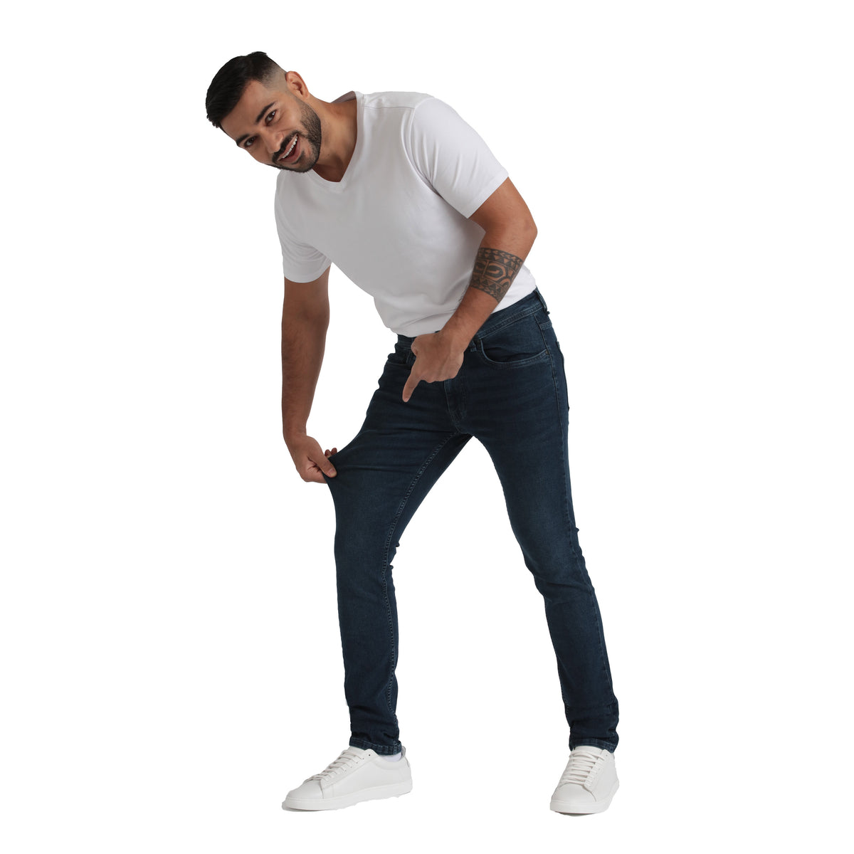 Man wearing white t-shirt and midnight blue skinny fit jeans with white sneakers.