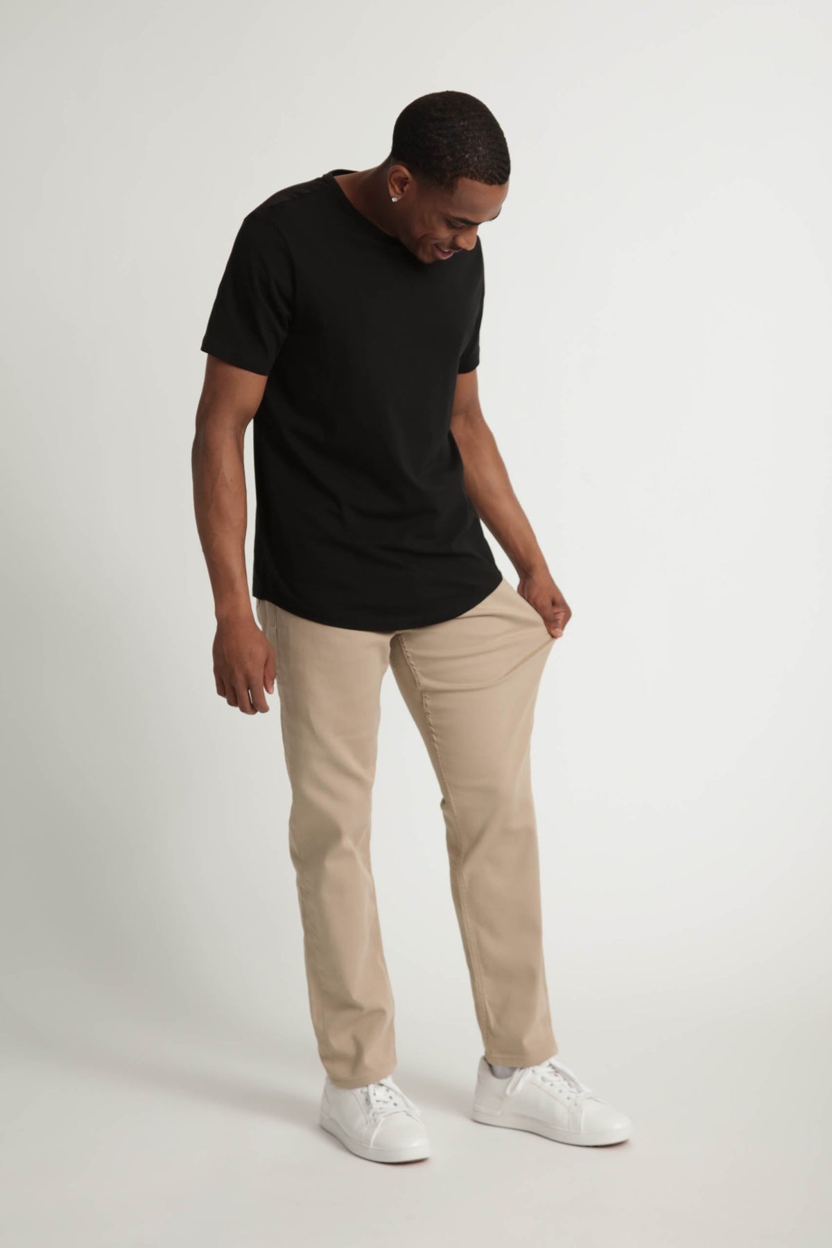Man wearing black short-sleeve t-shirt and light khaki slim fit pants with white sneakers.
